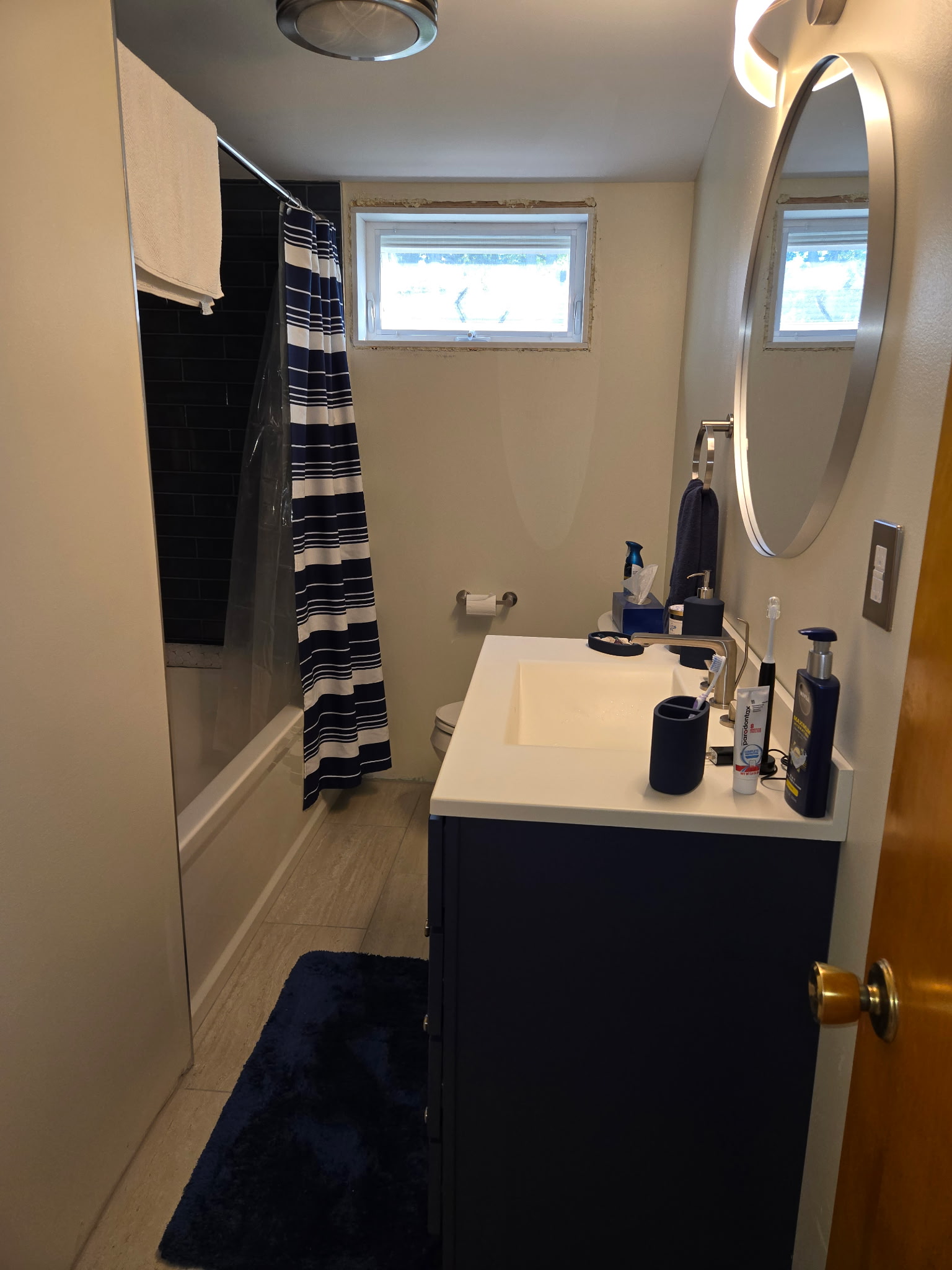 Finished bathroom remodel with navy vanity and black subway tile