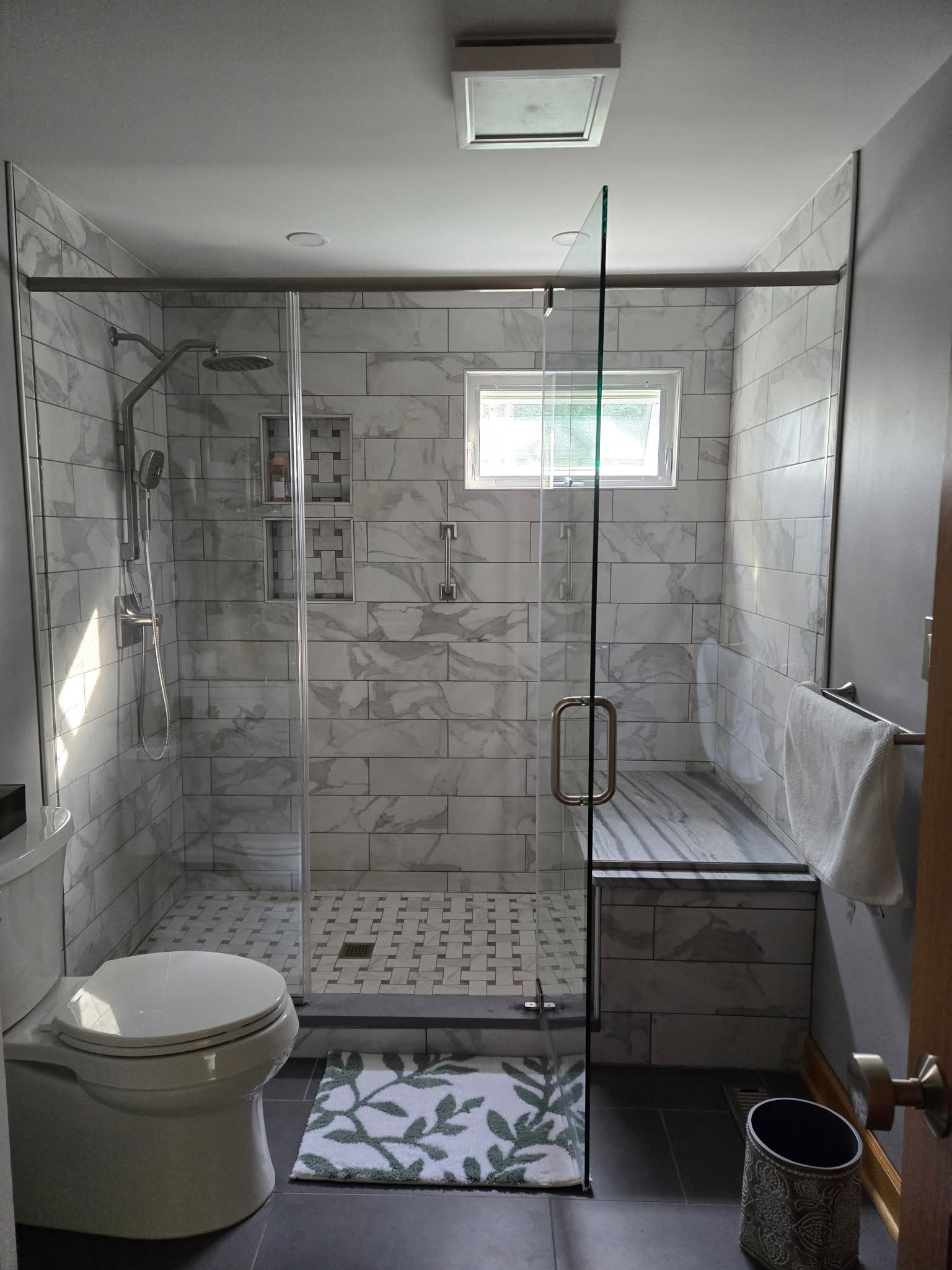 Stone-tile shower with glass doors and built-in bench
