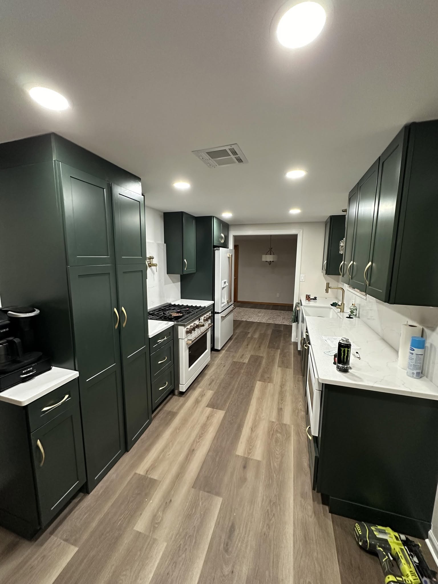 Finished kitchen remodel with green cabinets and quartz countertops